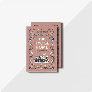 A stack of two books titled The Hygge Home by Liv Jensen featuring cozy log cabin and floral illustrations on the front cover