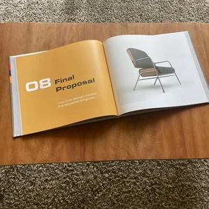 An open photo book showing furniture design, with one page displaying a modern chair image.