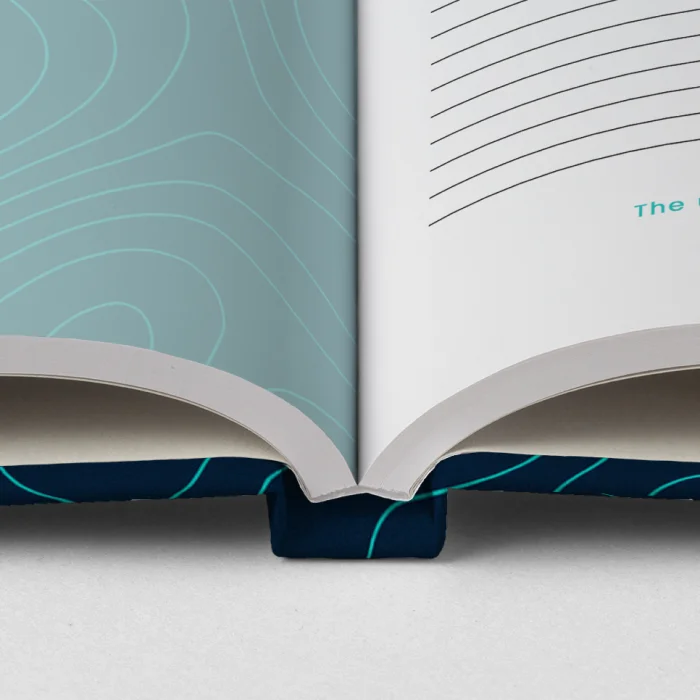 Ein aufgeschlagenes Notizbuch mit grünem bedrucktem Hardcover, in dem linierte Seiten mit großem Zeilenabstand zu sehen sind.