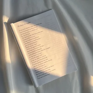 Zach Tomci's paperback poetry book, The Color of the Sun Behind Closed Eyes, folded open on a poem called 30 days of night