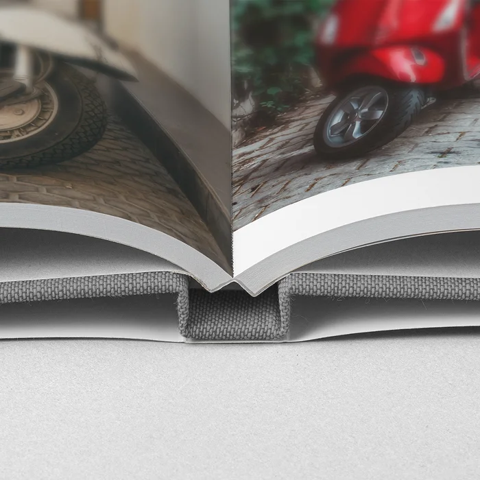 Close-up of linen hardcover photo book book with dust jacket, showing a sturdy spine and photo pages, wrapped in linen with a dust jacket.