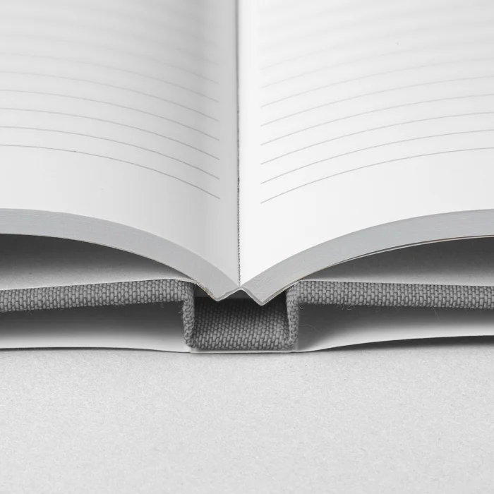 Ein aufgeschlagenes Hardcover-Notizbuch mit Schutzumschlag, in dem linierte Seiten zu sehen sind.