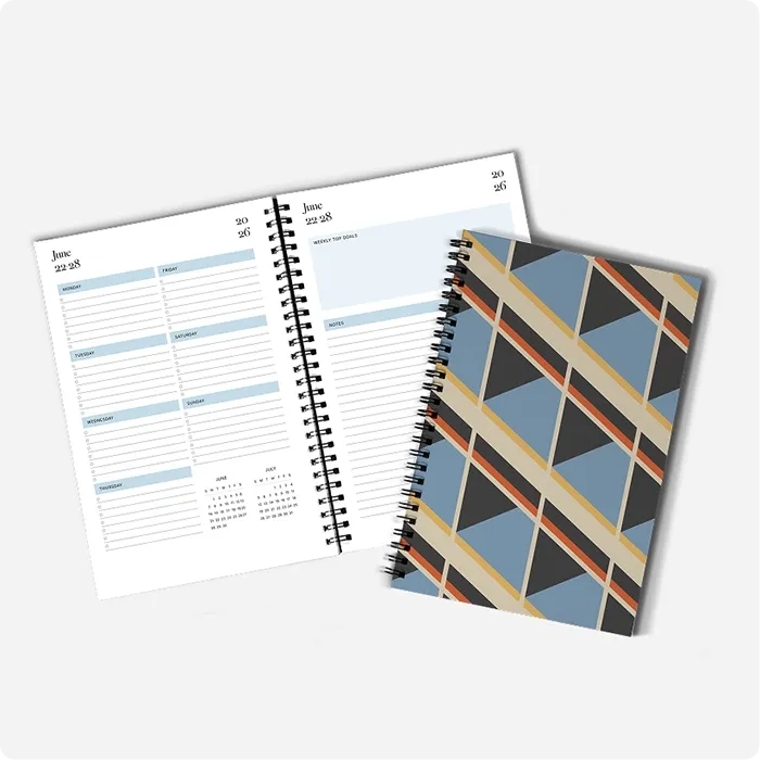 Two copies of a custom planner with Wire-O binding, one open on diary and scheduling pages, the other closed showing the geometric cover design