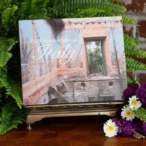 A photo book open to pages showing architectural photography in Italy, including a building exterior and some decorative flowers.