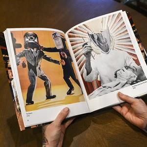 Hands holding open a photo book showing illustrated characters, including an action scene with figures.