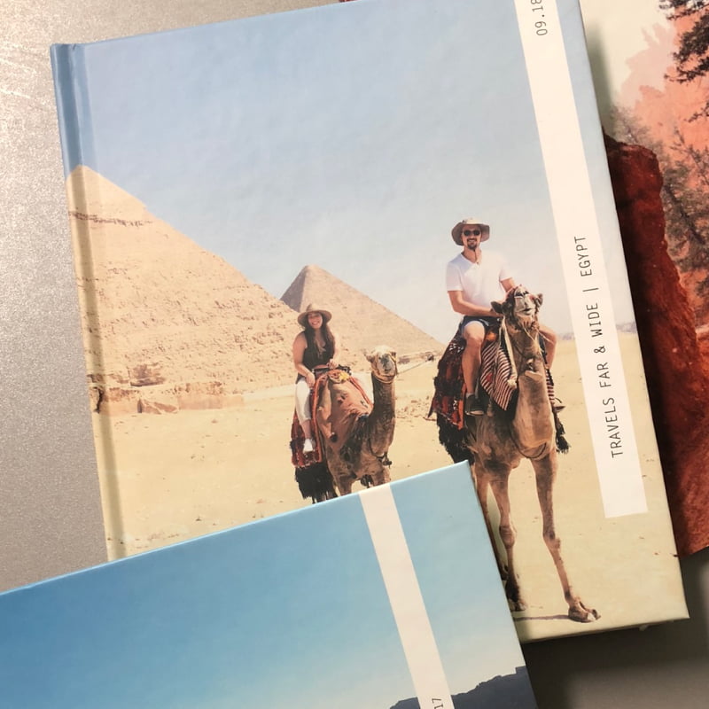 Professioneel reisfotoboek getiteld ‘Travels Far & Wide’ met twee mensen op de omslag die op kamelen rijden in Egypte