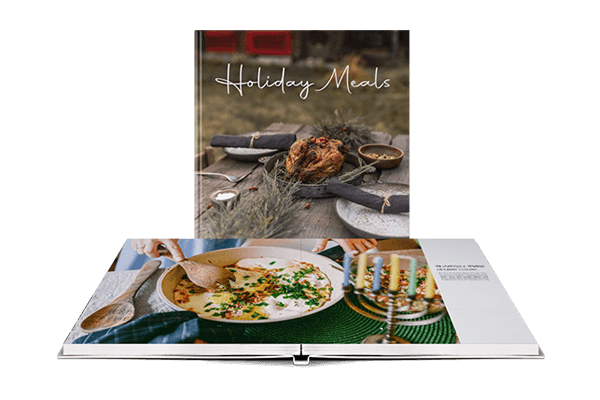 Ein aufgeschlagenes Layflat-Kochbuch, in dem ein Foto eines Festmahls abgebildet ist