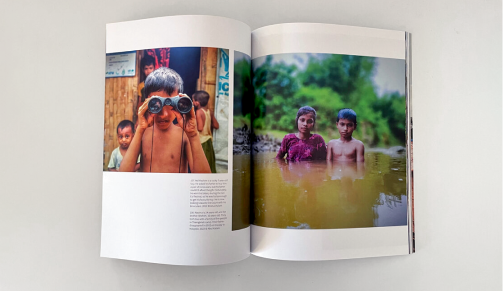 Custom magazine shown open featuring a child looking through binoculars on one page, two children standing waist-deep in a river on the opposite page.