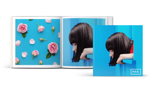 Capa de livro azul com mulher olhando para baixo. Livro aberto com rosas com fundo azul numa página, mulher em top vermelho e cabelo preto.